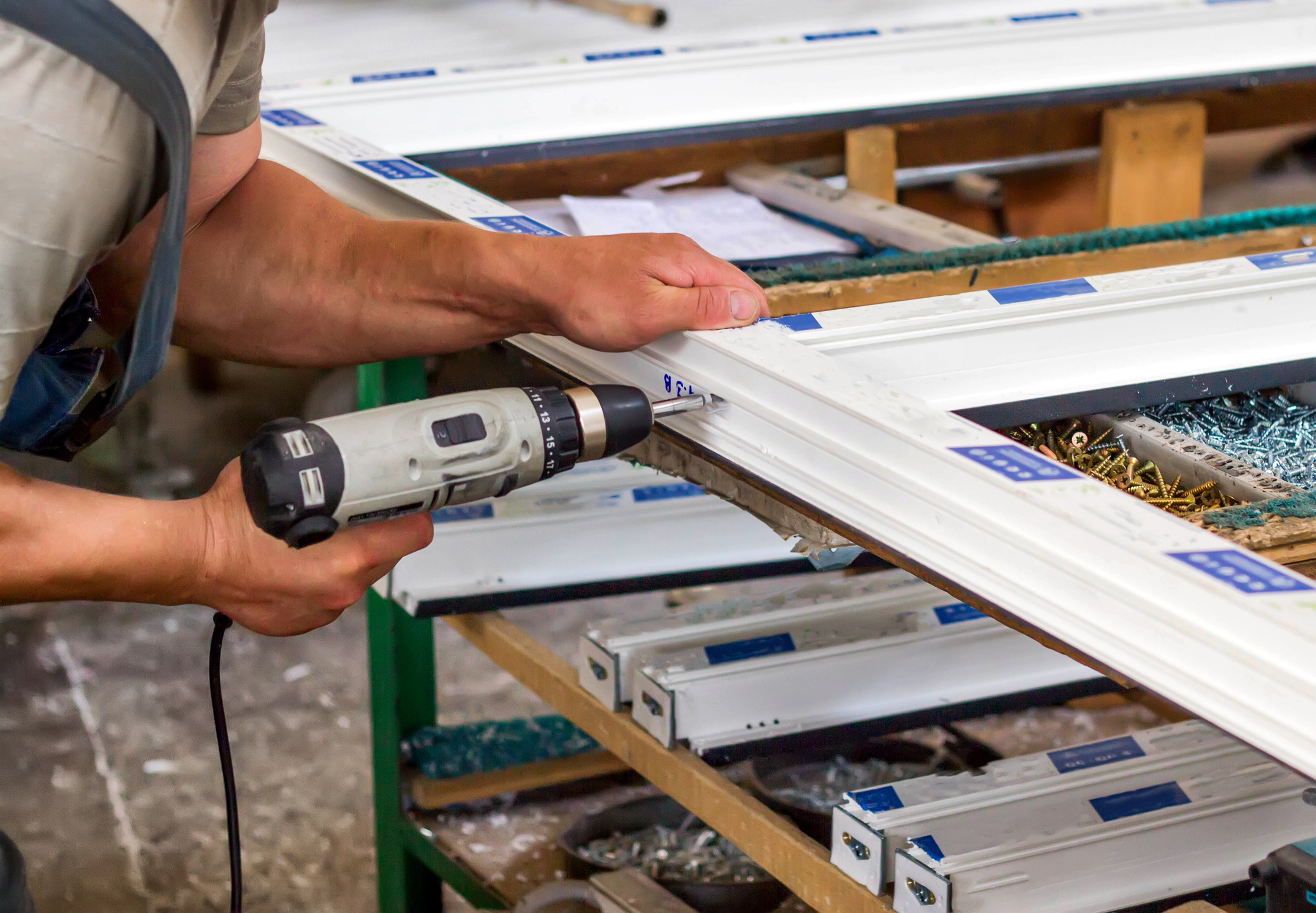 Production of pvc windows, a man screws a screwdriver into a pvc window, close-up, windows pvc